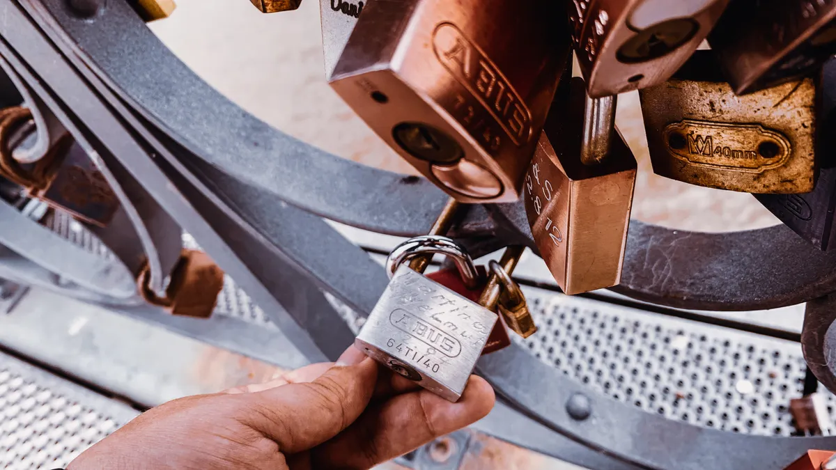 A hand holding a padlock among hanging locks