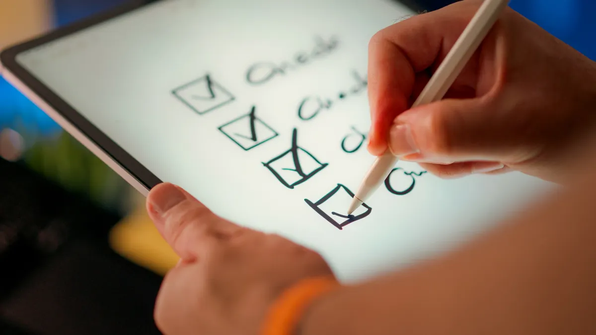 person marking checklist boxes on a tablet